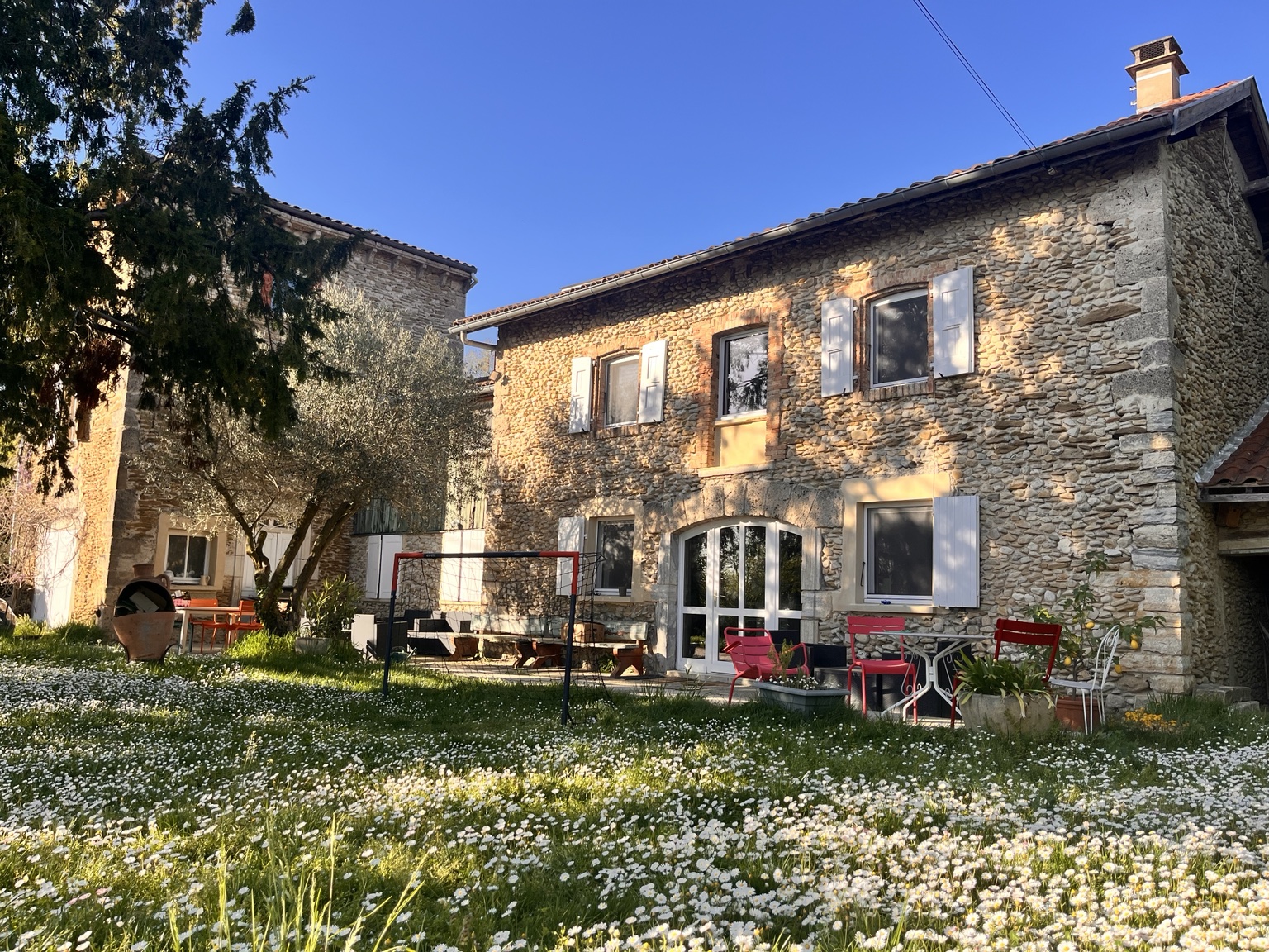 Façade en pierre de La Fenière Bleue et jardin fleuri